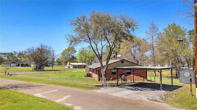 exterior space featuring aphalt driveway, a fenced front yard, a carport, a front lawn, and brick siding