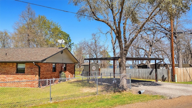 view of front of house with driveway, a front lawn, brick siding, an outbuilding, and fence