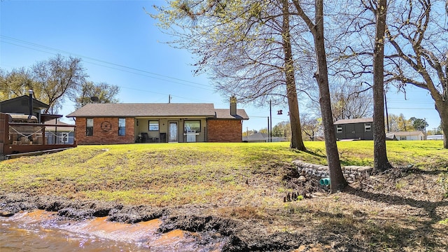 view of front of property with brick siding, a front yard, and a chimney