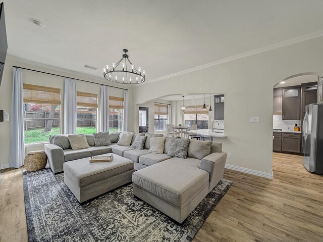 living area featuring stairway, a fireplace, crown molding, baseboards, and arched walkways