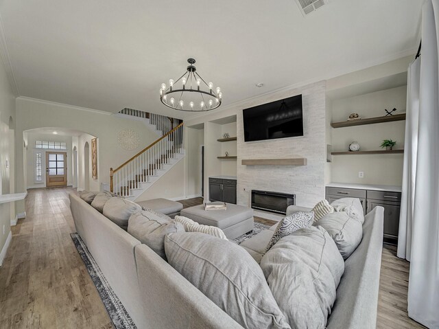 living area with a fireplace, a chandelier, ornamental molding, and baseboards