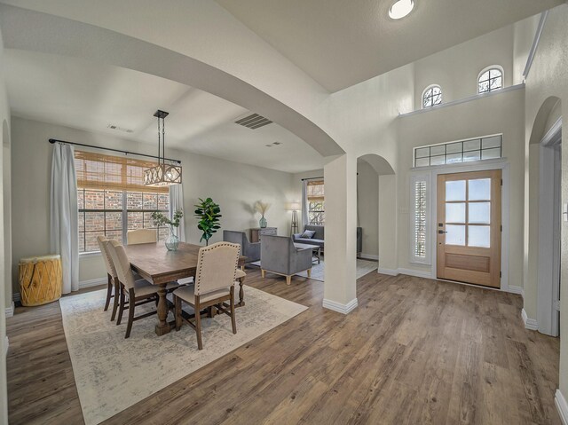 living area with arched walkways, visible vents, wood finished floors, and baseboards