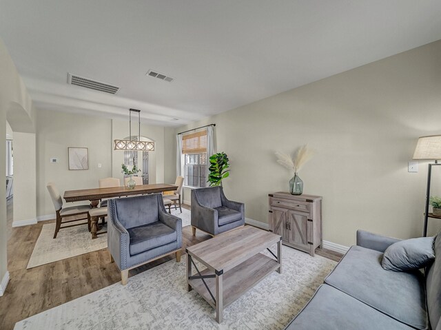 living room with baseboards, visible vents, and wood finished floors