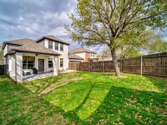 back of property with a shingled roof, a yard, a patio, and a fenced backyard