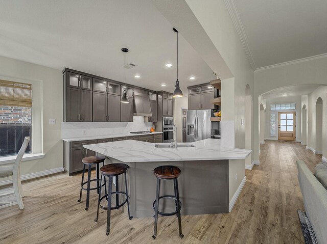 kitchen featuring a breakfast bar area, appliances with stainless steel finishes, a chandelier, arched walkways, and gray cabinets