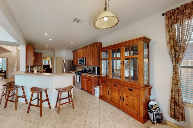 1312 Cattle Crossing Dr, Fort Worth, TX 76131 - kitchen with stainless steel appliances, a peninsula, a breakfast bar area, healthy amount of natural light, and recessed lighting