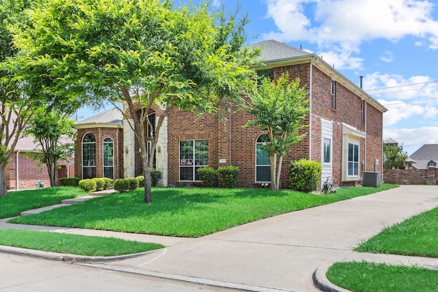 1192 Oak Hill Ln, Murphy, TX 75094 - traditional-style house featuring a front yard, brick siding, and central air condition unit