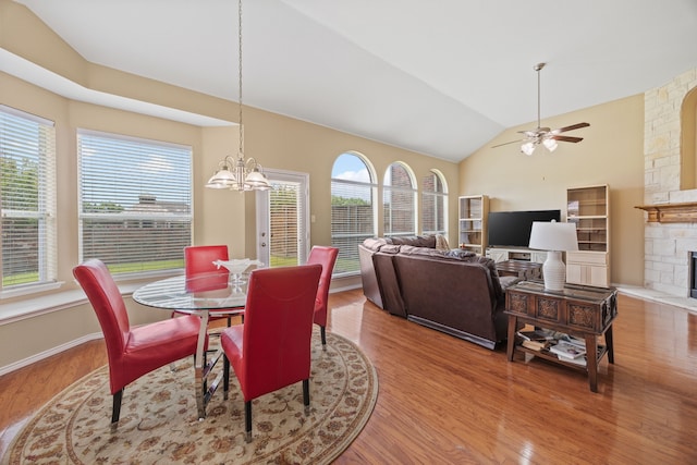 1192 Oak Hill Ln, Murphy, TX 75094 - dining area with vaulted ceiling, wood finished floors, a ceiling fan, a chandelier, and a stone fireplace