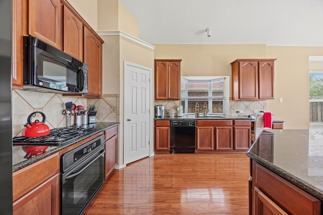 1192 Oak Hill Ln, Murphy, TX 75094 - kitchen with black appliances, dark stone counters, a sink, light wood finished floors, and decorative backsplash
