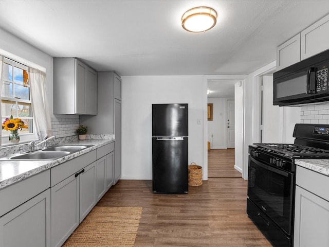 5536 Goodman Ave, Fort Worth, TX 76107 - kitchen featuring black appliances, a sink, tasteful backsplash, wood finished floors, and gray cabinetry