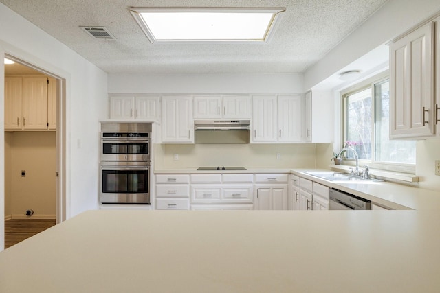 kitchen with visible vents, appliances with stainless steel finishes, under cabinet range hood, light countertops, and a sink