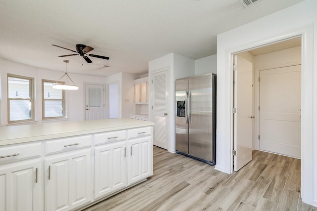 kitchen featuring stainless steel fridge, light countertops, a ceiling fan, white cabinetry, and light wood-style flooring