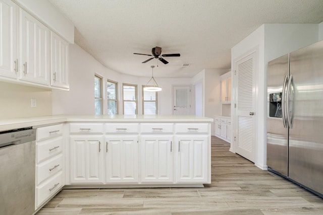 kitchen with a peninsula, ceiling fan, white cabinets, and stainless steel appliances