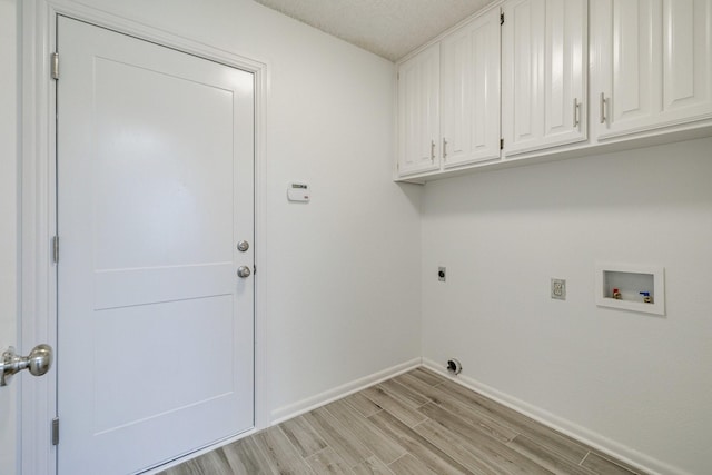 washroom with electric dryer hookup, washer hookup, light wood finished floors, baseboards, and cabinet space