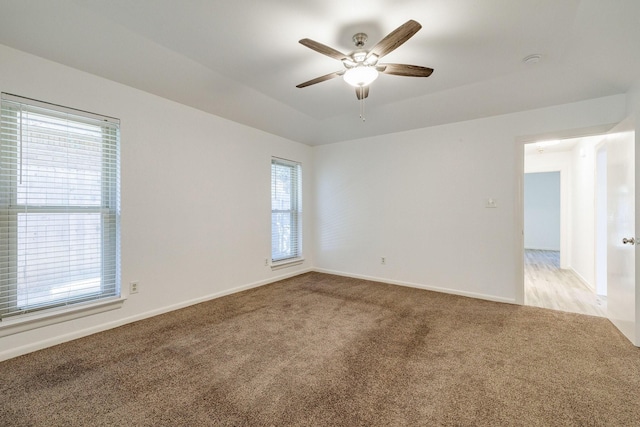 spare room featuring ceiling fan, light carpet, and baseboards