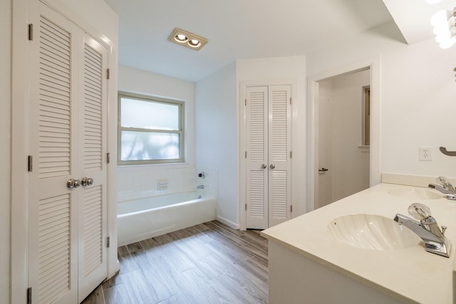 full bathroom with a sink, a closet, a bath, and wood finished floors