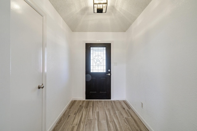 entryway featuring light wood-style flooring, baseboards, and a textured ceiling