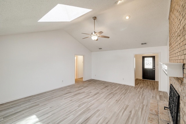 unfurnished living room with visible vents, vaulted ceiling with skylight, a ceiling fan, a textured ceiling, and light wood finished floors