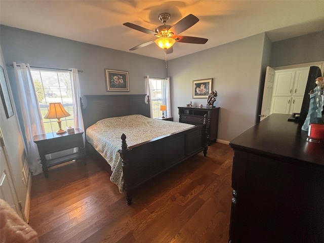 bedroom featuring multiple windows, baseboards, ceiling fan, and dark wood finished floors