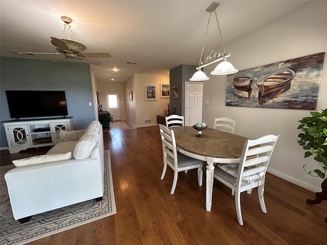 dining space featuring visible vents, a ceiling fan, baseboards, and dark wood-type flooring