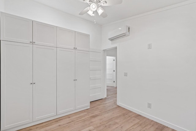 unfurnished bedroom featuring baseboards, light wood finished floors, a wall mounted AC, a closet, and crown molding