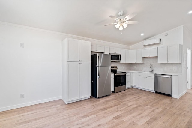 kitchen with a wall mounted air conditioner, a ceiling fan, a sink, stainless steel appliances, and vaulted ceiling