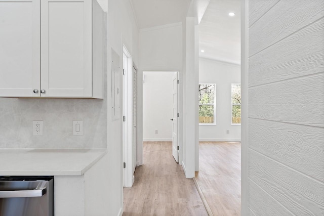 hallway featuring baseboards, lofted ceiling, and light wood-style floors