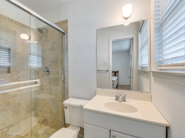 bathroom featuring a wealth of natural light, a stall shower, toilet, and vanity