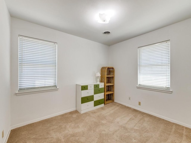 unfurnished room featuring light colored carpet, visible vents, and baseboards