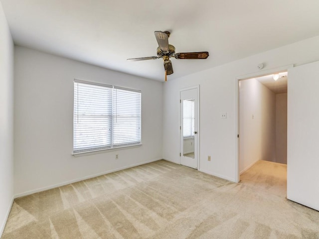 empty room featuring light carpet, baseboards, and ceiling fan