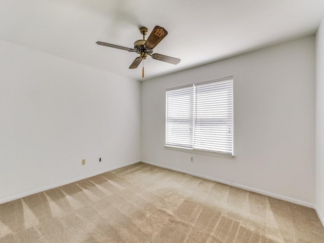 empty room featuring a ceiling fan, baseboards, and light carpet