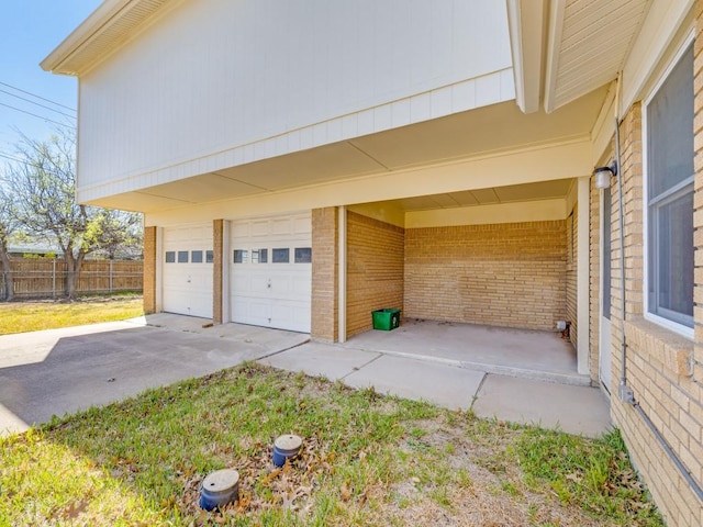 garage with concrete driveway and fence
