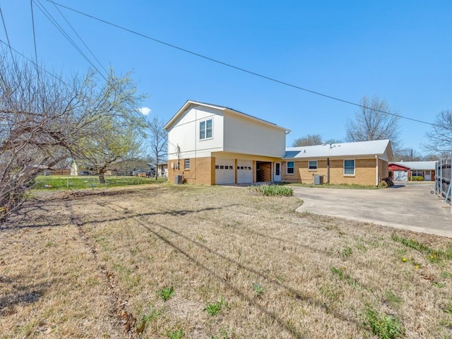 exterior space featuring brick siding, driveway, a front yard, and a garage