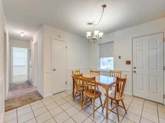 dining room featuring light tile patterned floors, visible vents, light colored carpet, and a chandelier
