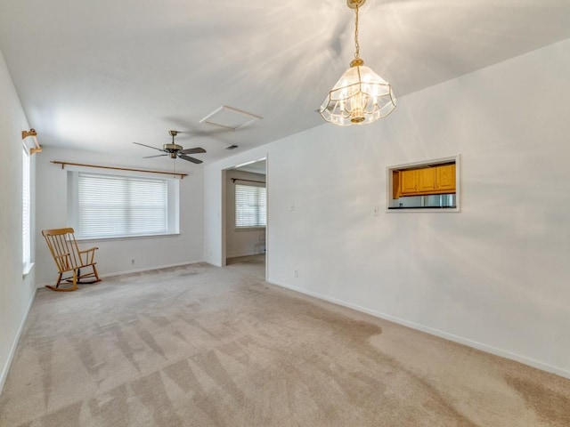 spare room featuring ceiling fan with notable chandelier, baseboards, and light carpet