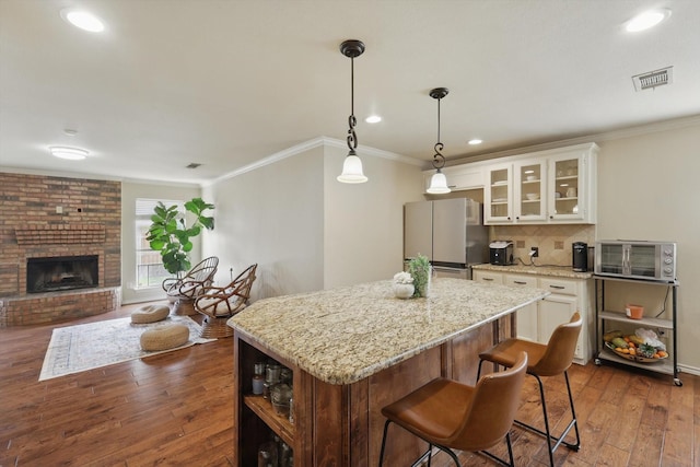 7732 Sagebrush Ct N, North Richland Hills, TX 76182 - kitchen featuring freestanding refrigerator, a kitchen island, dark wood-type flooring, decorative backsplash, and crown molding