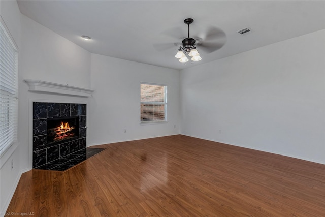 unfurnished living room with a ceiling fan, wood finished floors, a premium fireplace, baseboards, and visible vents