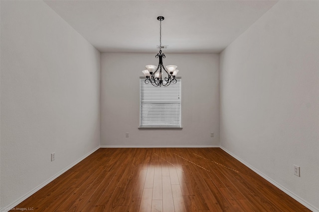 empty room with baseboards, wood-type flooring, visible vents, and a chandelier