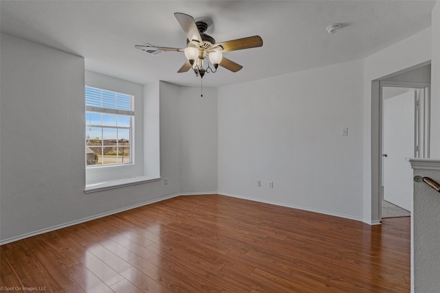 unfurnished room with a ceiling fan, visible vents, baseboards, and wood finished floors