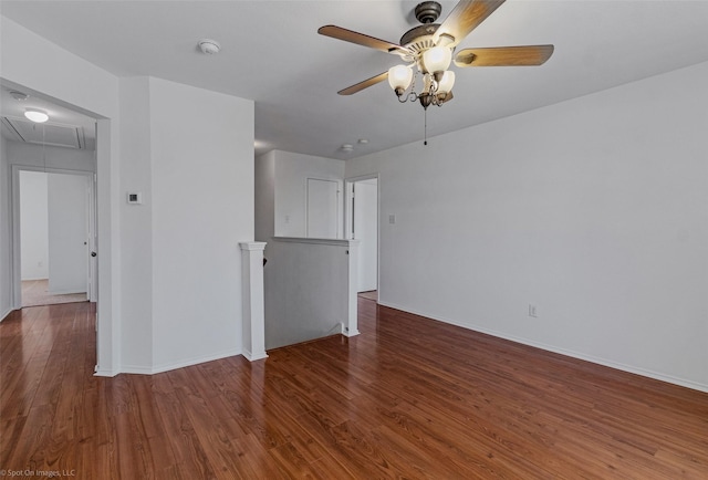 spare room with attic access, baseboards, wood finished floors, and ceiling fan