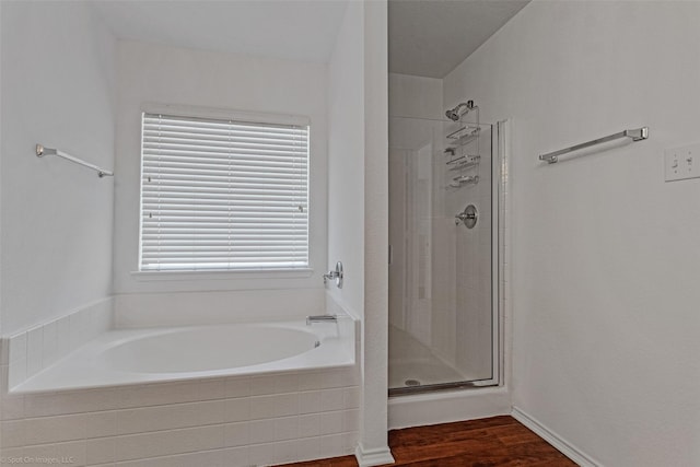 bathroom featuring wood finished floors, a garden tub, and a shower stall