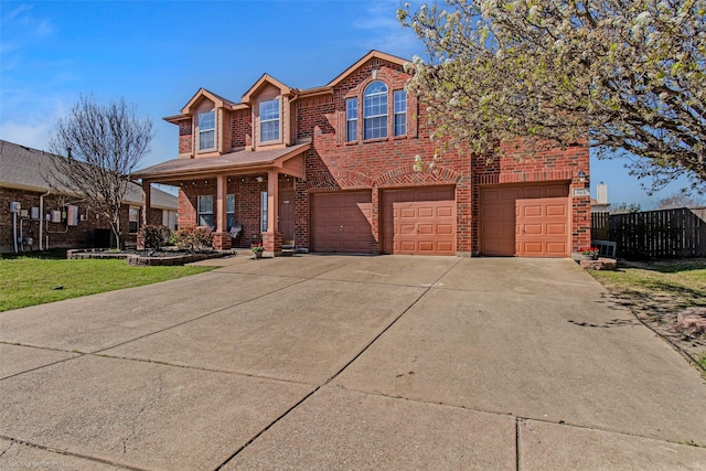 traditional-style house with concrete driveway, fence, a front lawn, brick siding, and a garage