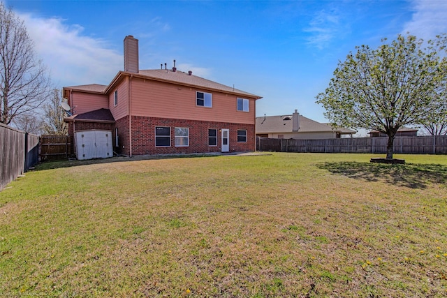 back of house featuring brick siding, a chimney, a fenced backyard, and a yard