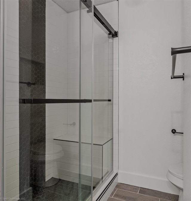 bathroom featuring toilet, a stall shower, and baseboards