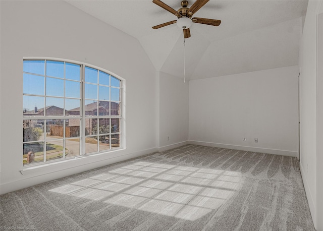 spare room with carpet flooring, a ceiling fan, baseboards, and vaulted ceiling
