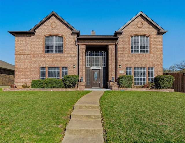 view of front facade featuring a front yard, fence, and brick siding