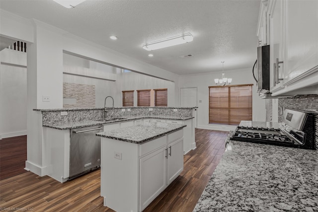 kitchen with white cabinetry, a sink, stainless steel appliances, and an inviting chandelier