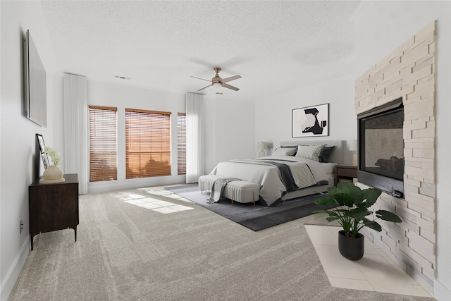 bedroom featuring a textured ceiling, visible vents, carpet, a ceiling fan, and a glass covered fireplace