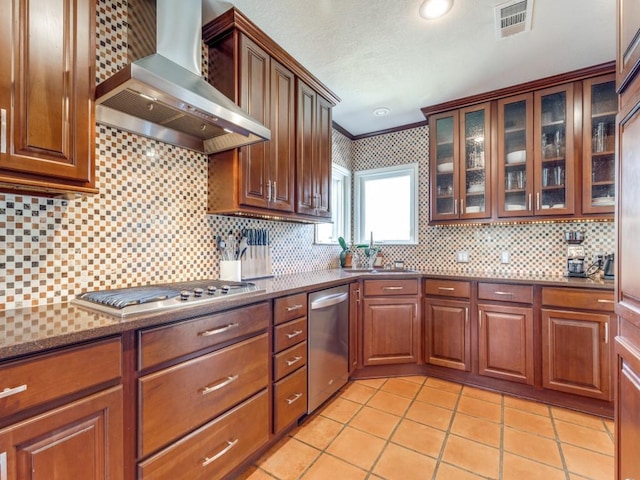 1410 Corto Dr, Dallas, TX 75218 - kitchen with wall chimney range hood, appliances with stainless steel finishes, light tile patterned flooring, tasteful backsplash, and glass insert cabinets