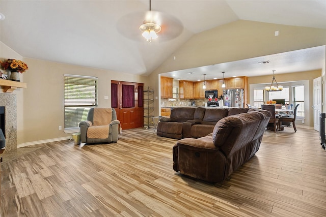 2718 Typhon Dr, Grand Prairie, TX 75052 - living room featuring light wood-style floors, vaulted ceiling, a tiled fireplace, and ceiling fan with notable chandelier